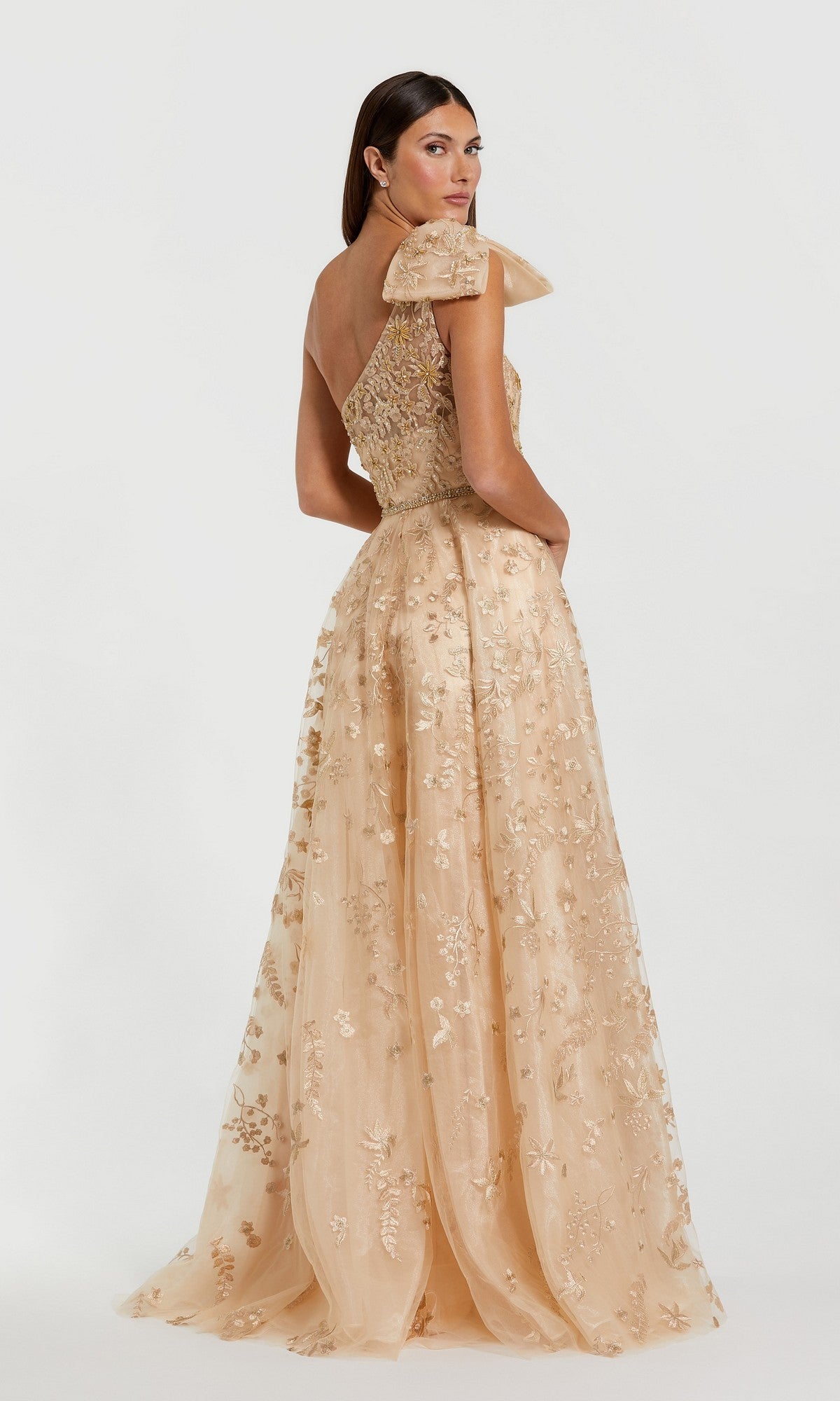 A woman models the Sage One-Shoulder Formal Dress (Mac Duggal 11177), a floor-length gown featuring beaded floral embroidery and a bow detail, against a plain white background.